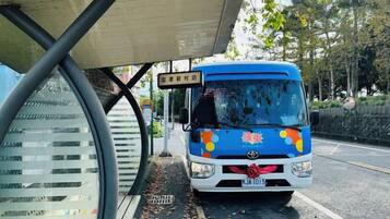 Un autobús azul estacionado bajo un refugio, con patente a la vista.