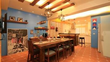 A kitchen with a dining table, chairs, and a hanging light fixture.