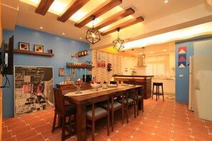 A kitchen with a dining table, chairs, and a hanging light fixture. - Mystery 13 Hostel (Yilan)