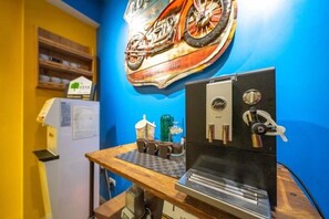 A kitchen area with a coffee machine, a refrigerator, and a wall-mounted motorcycle artwork. - Mystery 13 Hostel (Yilan)