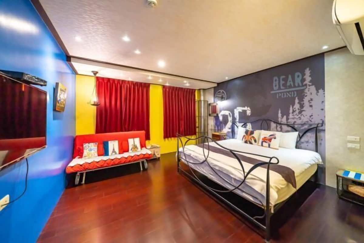 Ein Schlafzimmer mit einem Bett, einem roten Sofa und einem Wandbild.