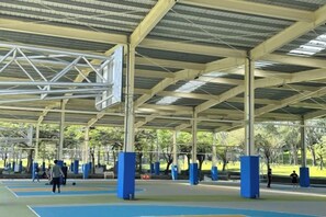 An outdoor basketball court with a covered roof, blue flooring, and several basketball hoops. - Mystery 13 Hostel (Yilan)