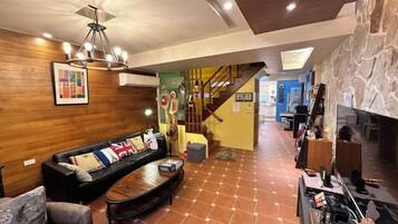 A living room with a sofa, a coffee table, and a fireplace. There is a staircase leading to another level.