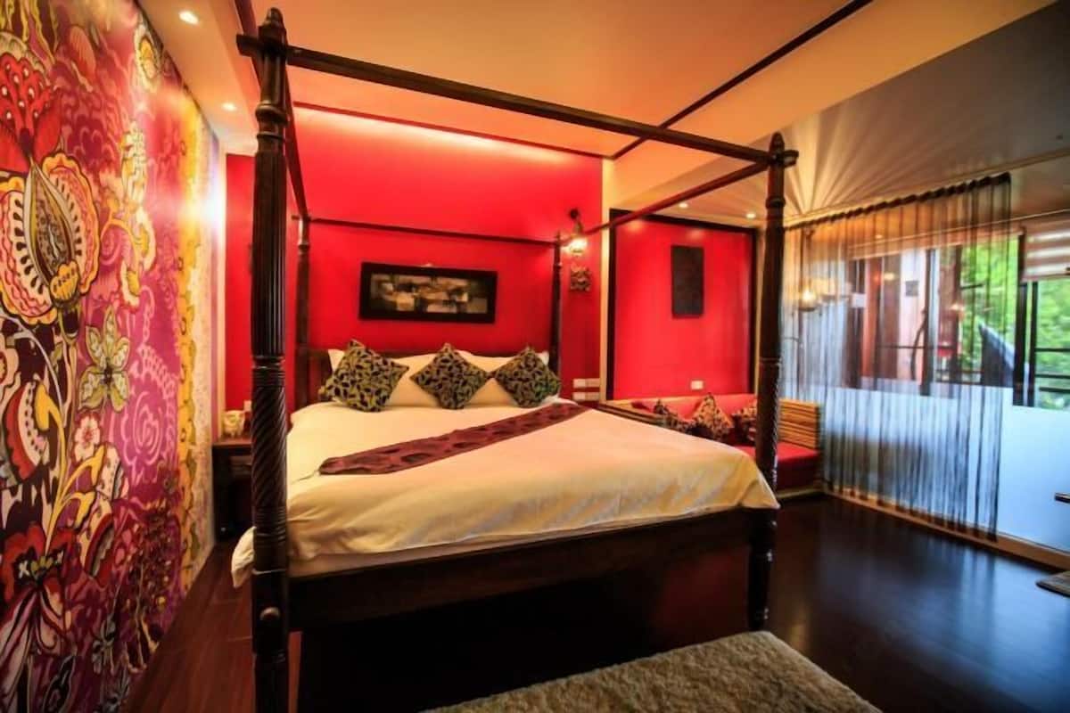 Ein Himmelbett mit roter Wand und einem großen Fenster.