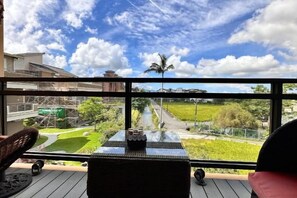 A balcony with a view of a green landscape and a clear sky.