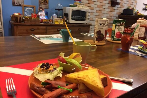 A breakfast plate with sausages, a grilled cheese sandwich, and a cup of coffee on a red placemat. - Mystery 13 Hostel (Yilan)