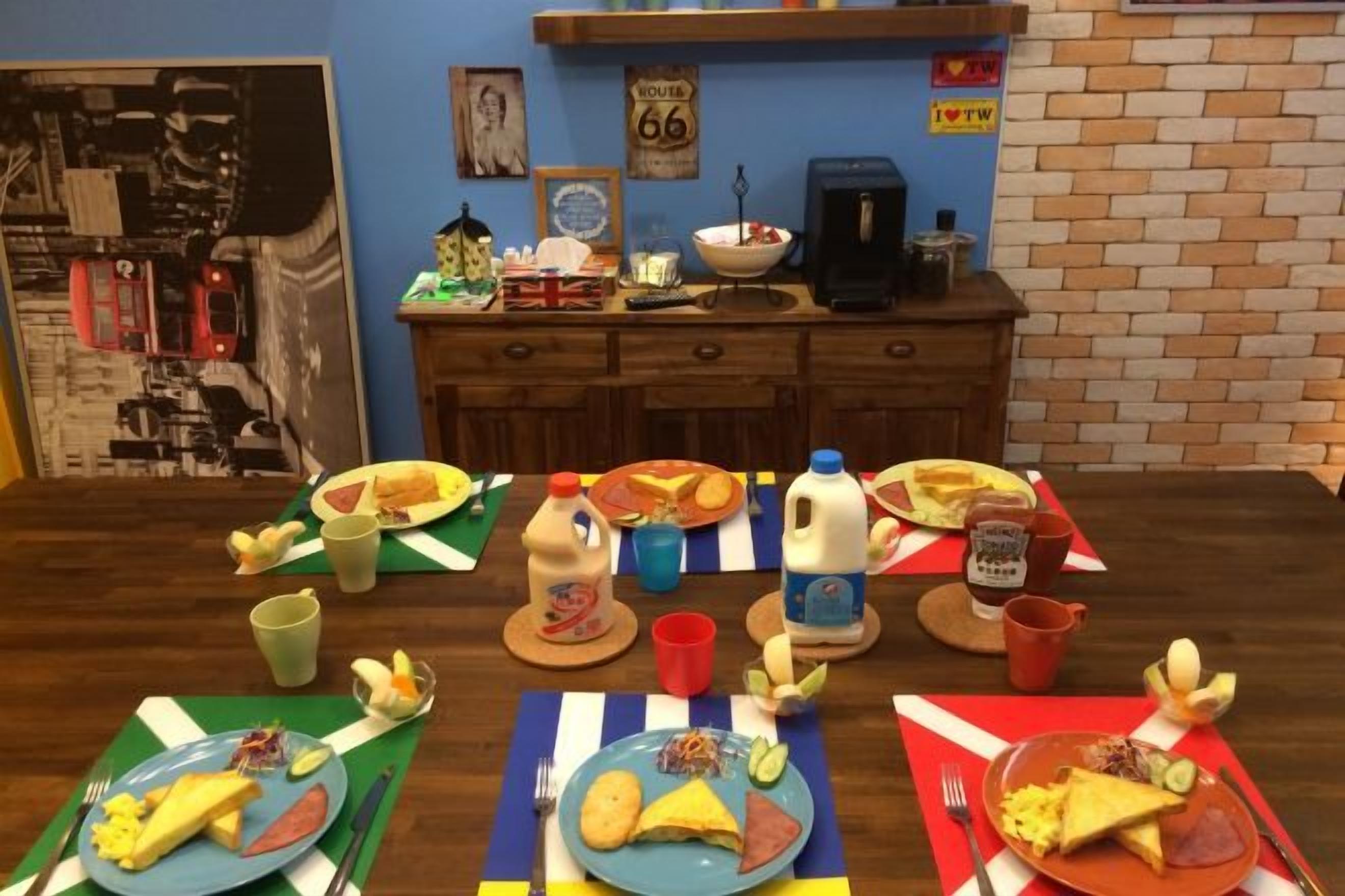 A dining table with plates of food, cups, and a milk jug.