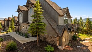 A modern house with a sloped roof, stone foundation, and a well-maintained garden with various plants and a pathway.