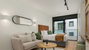 A modern living room with a sofa, a coffee table, and a bed with a headboard. - The Sage l Studio l New Development (Cape Town)