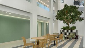 A modern indoor space with a checkered floor pattern, wooden furniture, and a large tree. - The Sage l Studio l New Development (Cape Town)