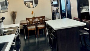A modern kitchen with a central island, dark cabinetry, and a ceiling fan.