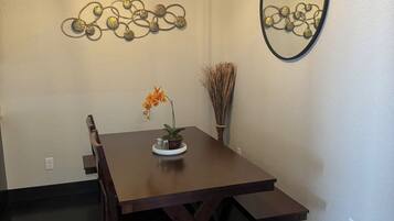 Un comedor con mesa de madera, sillas, ventilador de techo, adornos en la pared y un espejo.