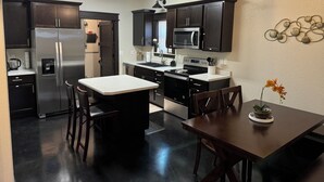 A modern kitchen with dark cabinetry, stainless steel appliances, and a central island with seating.
