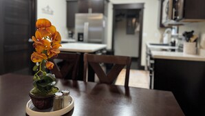 A kitchen with a dining table, chairs, and a potted plant with flowers.