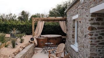 Un bâtiment en pierre doté d’une pergola et d’un espace extérieur aménagé pour s’asseoir.