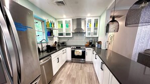 Een moderne keuken met roestvrijstalen apparatuur, witte kasten en een houten vloer.