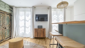 Ein modernes Wohnzimmer mit Holzschrank, Flachbildfernseher, rundem Hocker und Barstuhl.