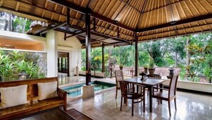 A covered outdoor area with a pool, wooden furniture, and potted plants. - Natura Villa Ubud Bali (Bali)