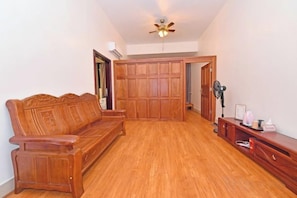 A room with a wooden floor, a wooden sofa, a ceiling fan, and a wooden cabinet. - Taichang Hotel (Yangjiang)