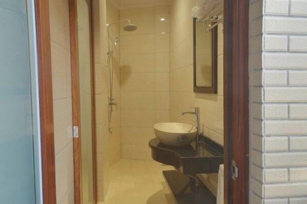 A modern bathroom with a glass shower enclosure, a white sink, and a mirror above the sink.