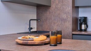 A kitchen counter with a plate of waffles, two glasses of orange juice, and a coffee maker. - Tropic Night Apartment by Litto (Split)