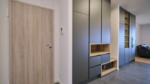 A modern interior with a wooden door, grey cabinets, and a black sofa. - Tropic Night Apartment by Litto (Split)
