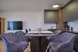 A modern kitchen with a central island, dark cabinets, and a flat-screen TV mounted on the wall. - Tropic Night Apartment by Litto (Split)