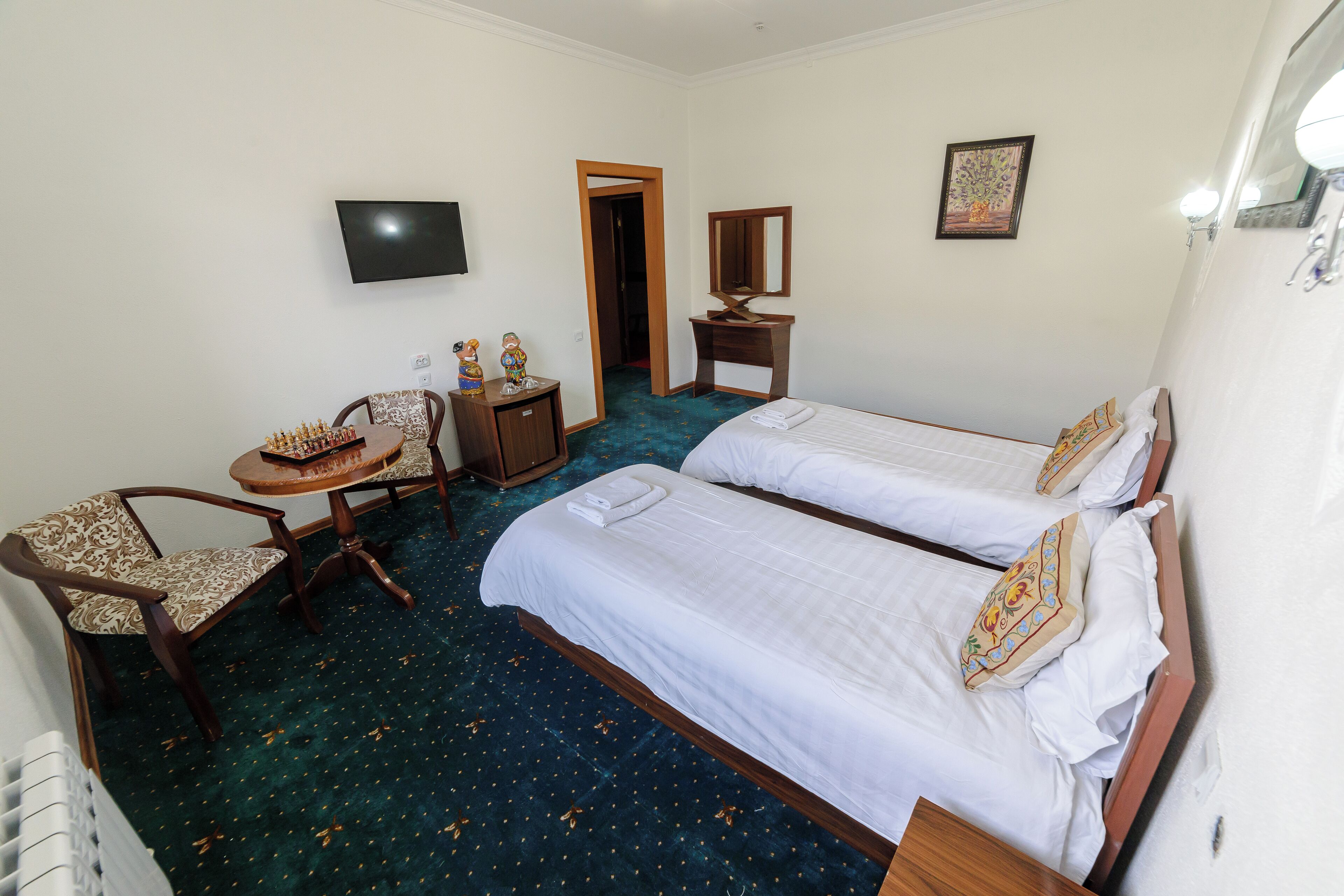 A hotel room with two beds, a desk, a chair, a TV, and a mirror.