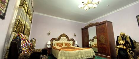 Een slaapkamer met een groot bed, een kroonluchter, een kledingkast en een etalagepop.