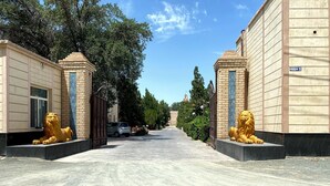 Un sendero que conduce a un edificio flanqueado por dos estatuas doradas de leones.