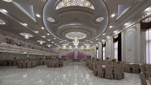 Un salón de baile imponente con techo alto, candelabros ornamentados y suelo de mármol pulido.