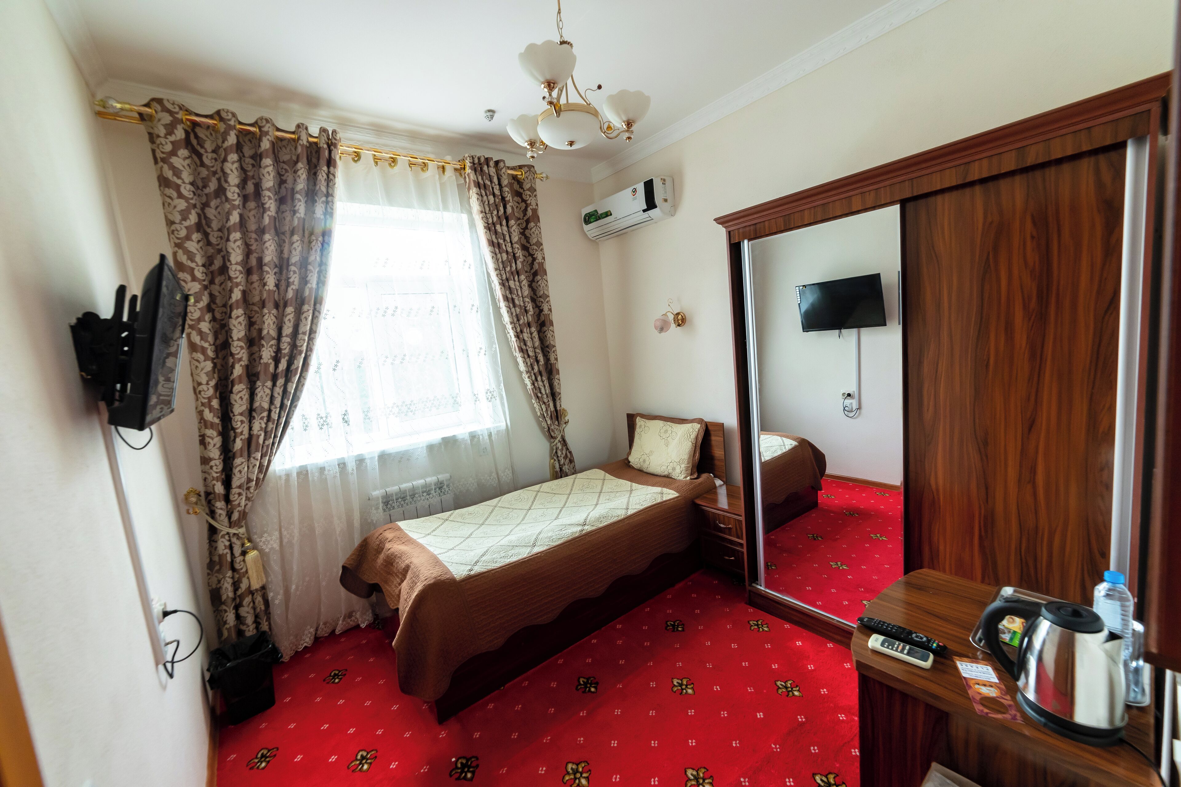 Une chambre d’hôtel équipée d’un lit, d’une table de chevet avec une bouilloire, d’une télévision et d’un appareil de climatisation.