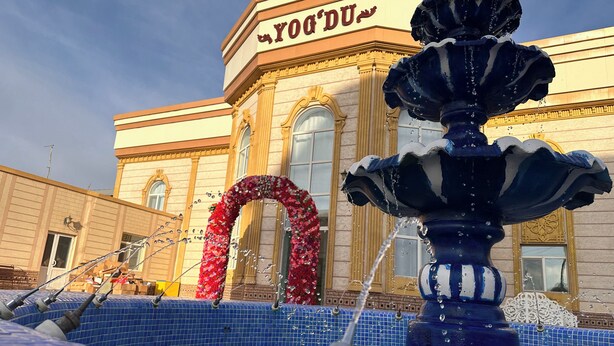 Una fuente con chorros de agua frente a un edificio con un letrero que dice "YODU".