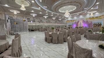 Un gran salón de banquetes con suelos de mármol, candelabros ornamentales y un decorado llamativo.