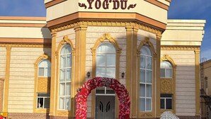 Un edificio con un letrero que dice "YOG'DU" y un arco de entrada adornado con motivos florales.