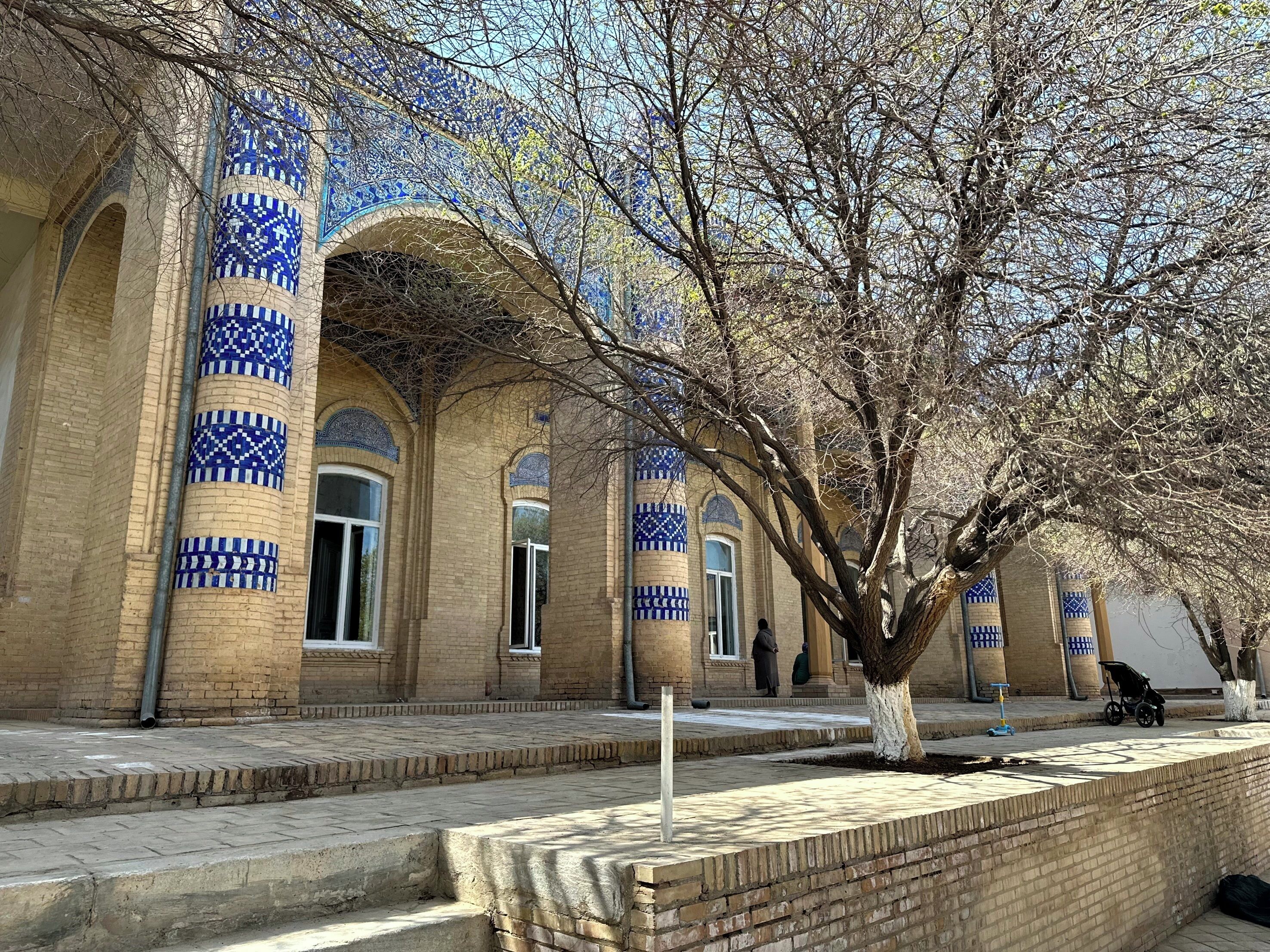 A courtyard with a tiled building featuring arches and blue patterns.