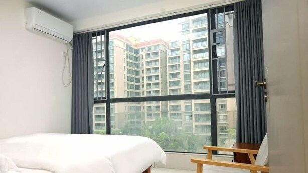 Una habitación de hotel con una cama, una mesita de madera, una ventana con vista a rascacielos y un equipo de aire acondicionado.