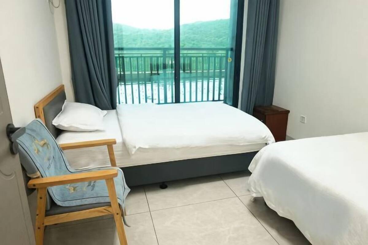 A hotel room with a bed, a chair, and a view of a balcony.
