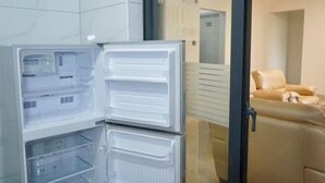 Una cocina moderna con refrigerador empotrado, un lavamanos doble y un sofá beige en el área de estar contigua.