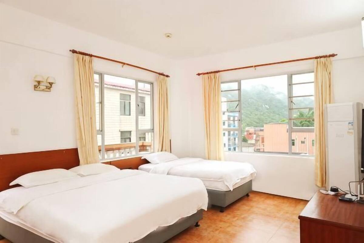 A hotel room with two beds, a desk, a chair, and a window with curtains.