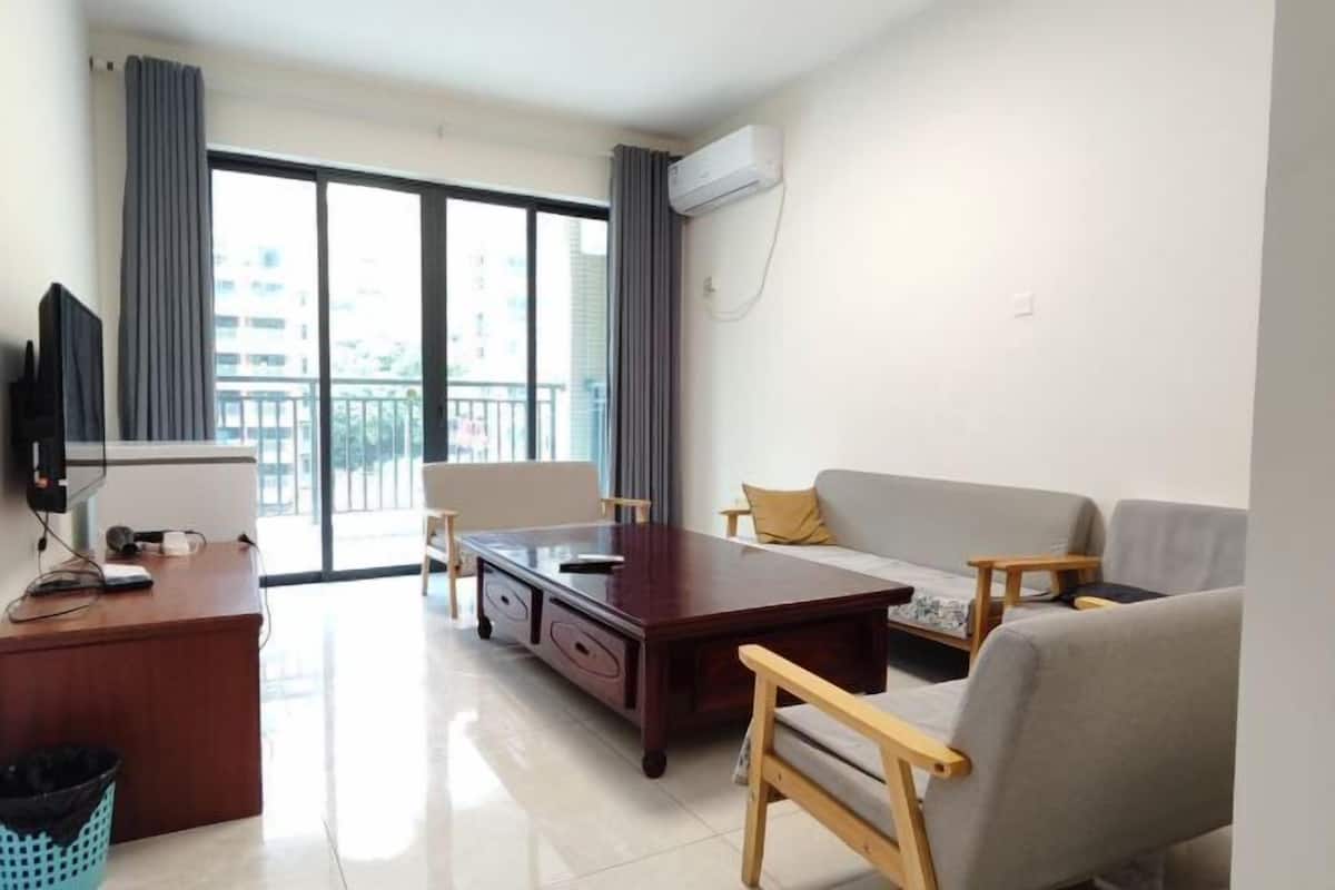 A living room with a sofa, a coffee table, a TV, and a desk.