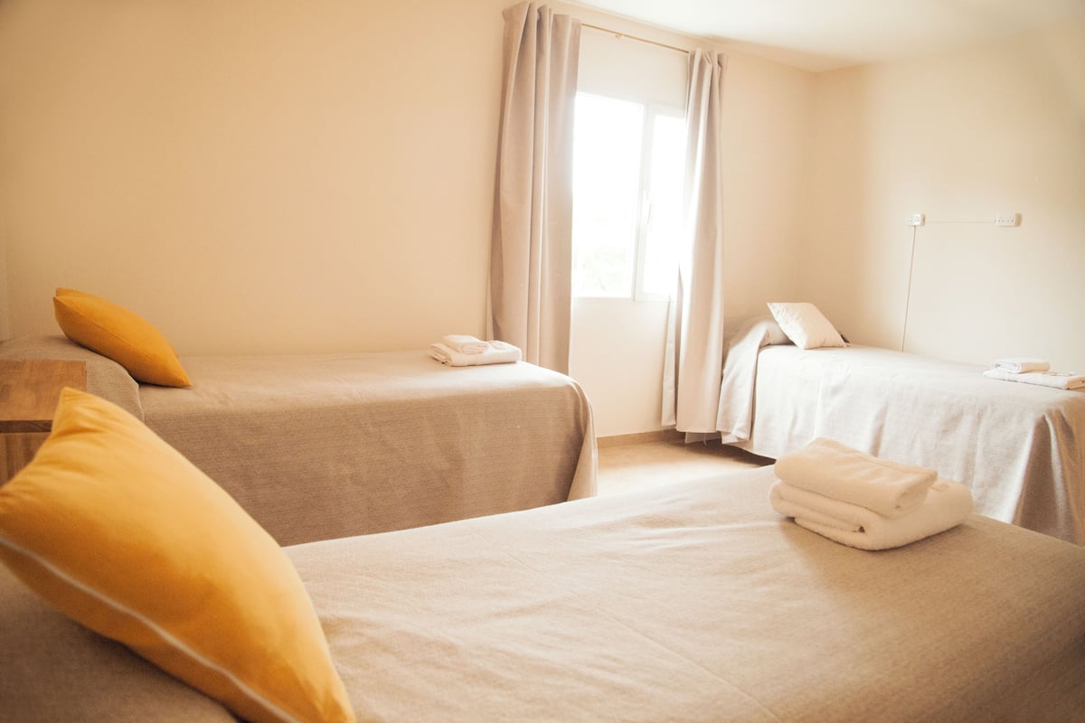 Una habitación de hotel con dos camas, una ventana con cortinas y una mesita de noche con toallas.