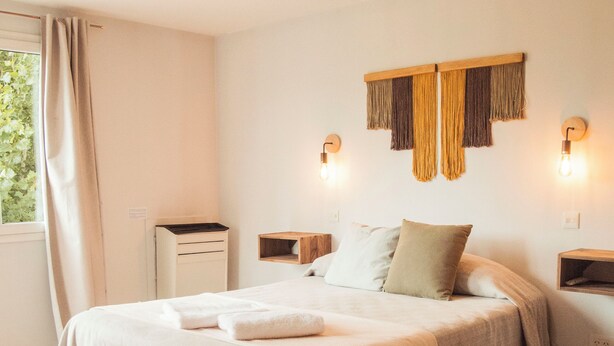 Ein Schlafzimmer mit einem großen Bett, Nachttischen, einer Holzbank und einem Schreibtisch.