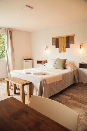A bedroom with a large bed, bedside tables, a wooden bench, and a desk. - Alameda (El Calafate)