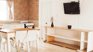 Ein modernes Wohnzimmer mit einem Holztisch, einem beigefarbenen Sessel und einem an der Wand montierten Fernseher.