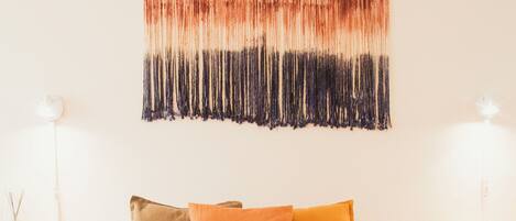 A neatly made bed with two folded towels, a wooden headboard, and a wall hanging above.