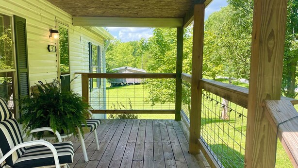 Une terrasse en bois avec une rambarde, une chaise et un pot de fleurs.