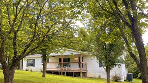 Une maison à deux étages avec une terrasse en bois et un porche couvert.