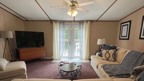 Un salon doté d’un ventilateur de plafond, d’un téléviseur à écran plat, de deux canapés, d’une table basse et d’une lampe.