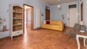 A living room with a yellow sofa, a wooden cabinet, and a patterned chair. - Il Cortile degli Aragonesi by Wonderful Italy (Palermo)